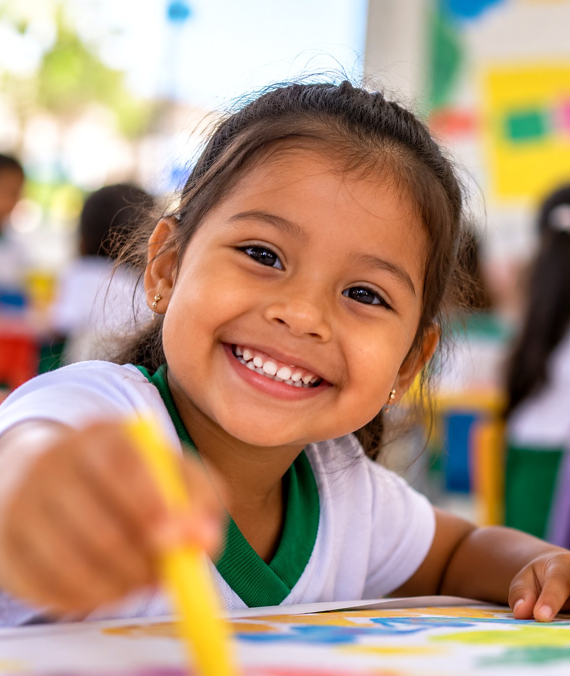 Niña sonriendo mientras pinta en clase